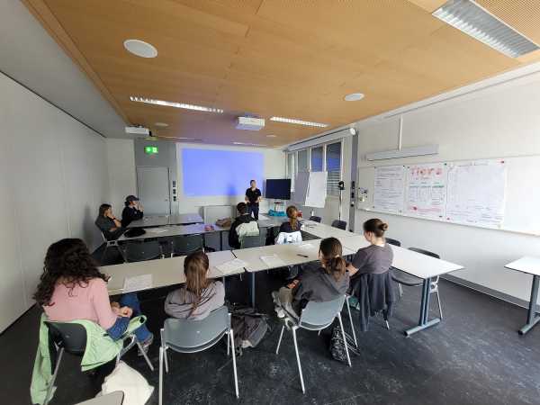 Room with people, person presenting in front of a screen