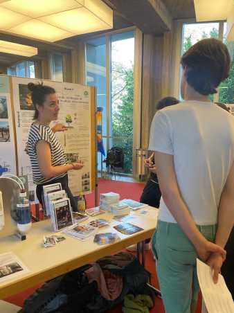 Woman standing in front of poster, explaining the content to students