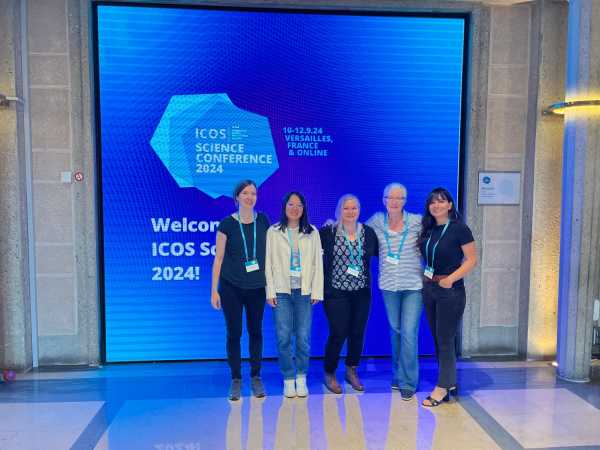 Group picture of five women in front of conference welcome screen