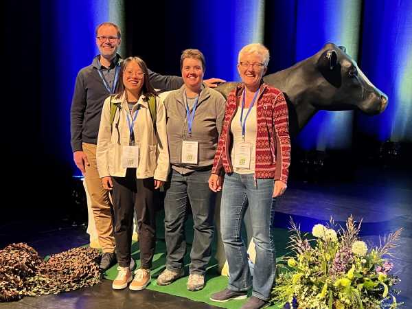 Four people in front of model cow