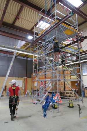 Three people climbing on a scaffold