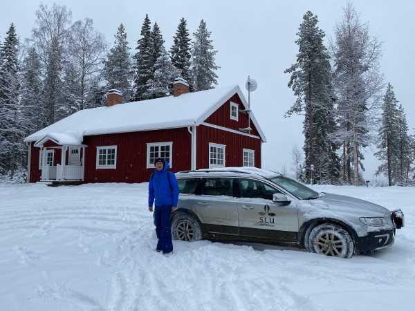Man in front of car and house in the snow