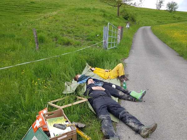 Three people sleeping on the side of a field path