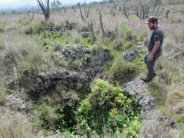 Man next to lava tube opening