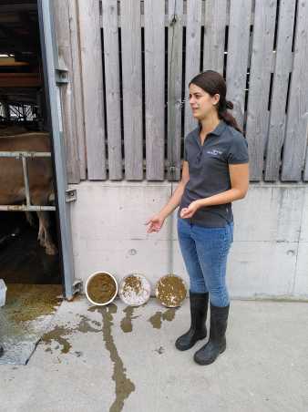 Woman pointing to three sieves with faeces