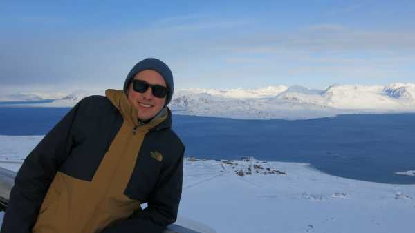 Man in the foreground, village of Ny-Alesund int the background