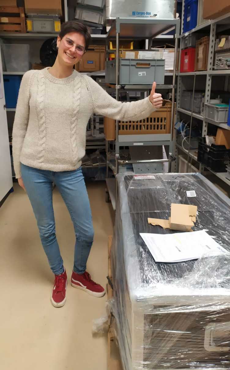 Woman giving a thumbs up next to a big box