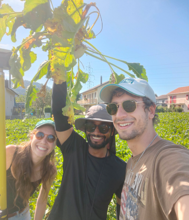 Selfie of three people smiling into the camera, one holding a sugar beet plant