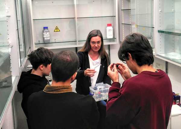 Woman showing small bottles to three young men