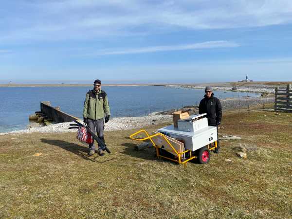 Two men, a full trolley, sea in the back