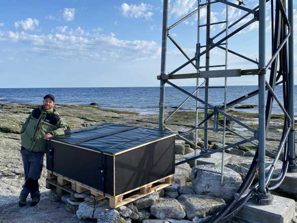 Man leaning on box, sea in the back