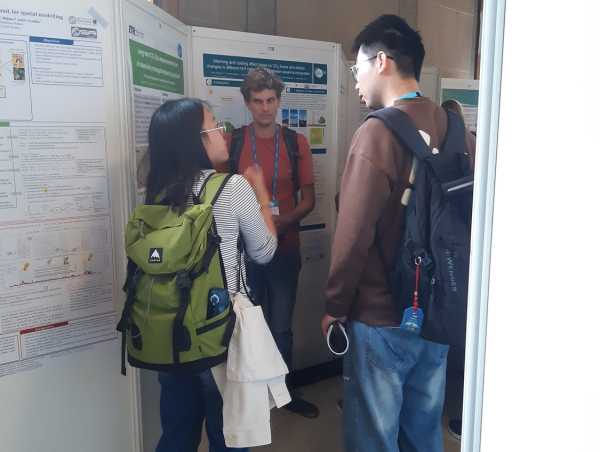 Woman explaining her poster to two persons