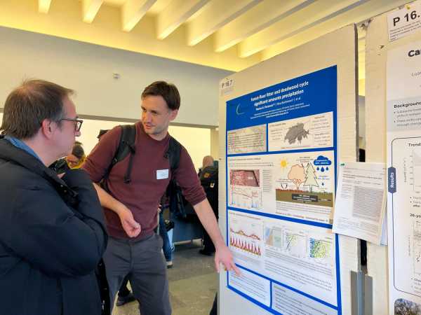 Man pointing at something on his poster, explaining it to another man