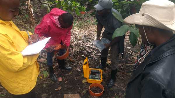 People standing around a chamber in the ground, yellow box with measurement device is connected