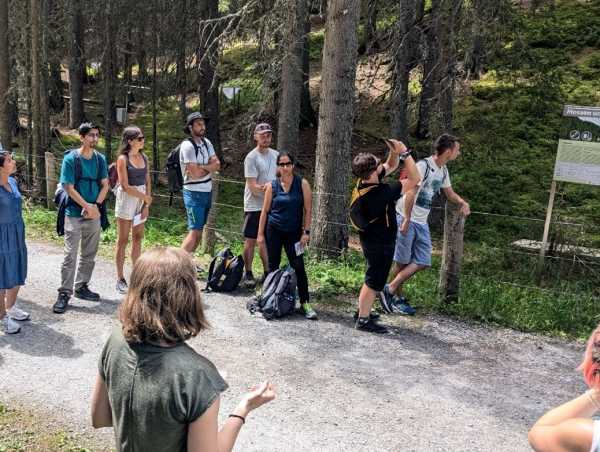 Woman explaining something to a group of people on a forest road